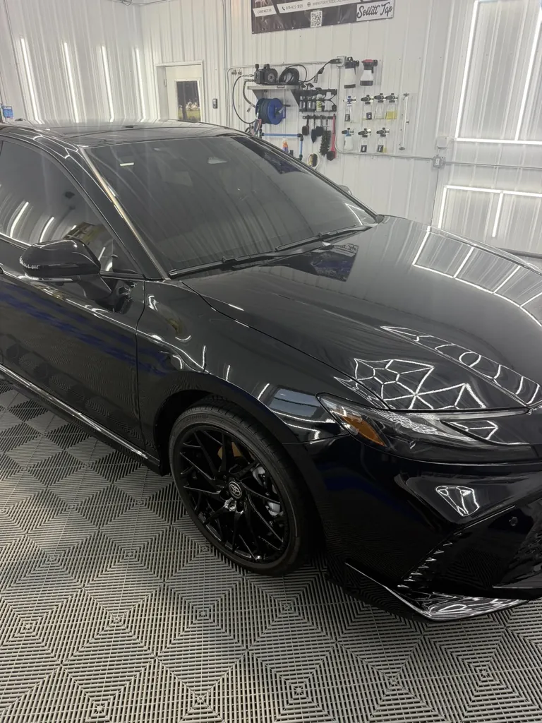 Black coupe with a mirror-like finish inside the Porter's Detailing shop